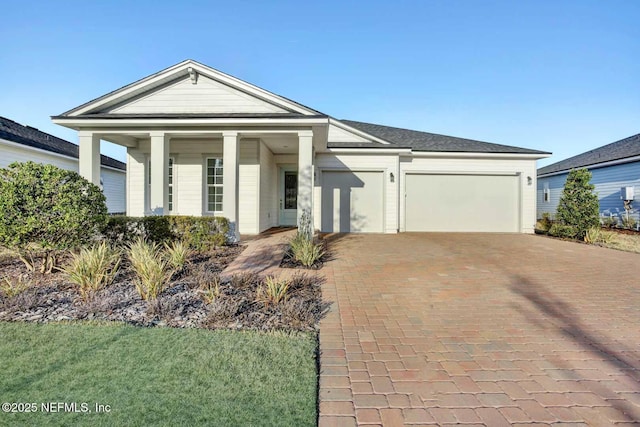 neoclassical home featuring an attached garage, a front lawn, and decorative driveway