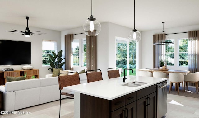 kitchen featuring dark brown cabinets, ceiling fan, a kitchen island with sink, sink, and hanging light fixtures