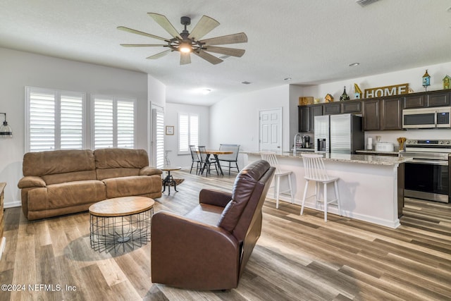 living room with ceiling fan, light hardwood / wood-style flooring, and a textured ceiling