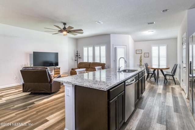 kitchen with dark brown cabinetry, sink, a center island with sink, hardwood / wood-style flooring, and dishwasher