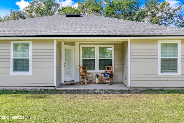 rear view of house featuring a lawn and a porch