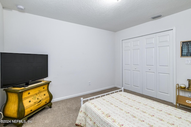 bedroom with a closet, carpet floors, and a textured ceiling