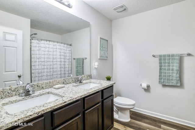 bathroom featuring hardwood / wood-style floors, a textured ceiling, toilet, vanity, and a shower with shower curtain