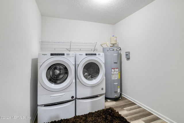 washroom with water heater, light hardwood / wood-style floors, a textured ceiling, and independent washer and dryer