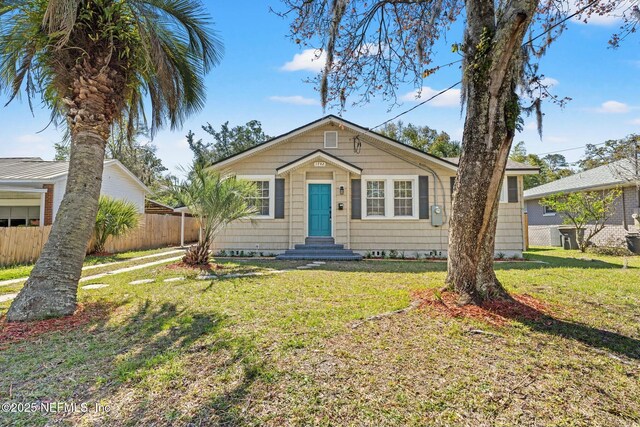 bungalow-style house featuring entry steps, a front lawn, and fence