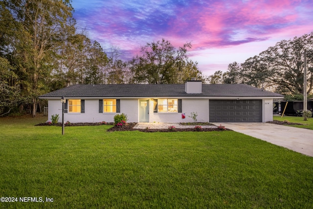 ranch-style house featuring a yard and a garage