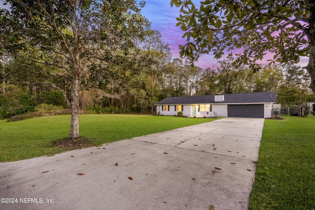 ranch-style home featuring a lawn and a garage