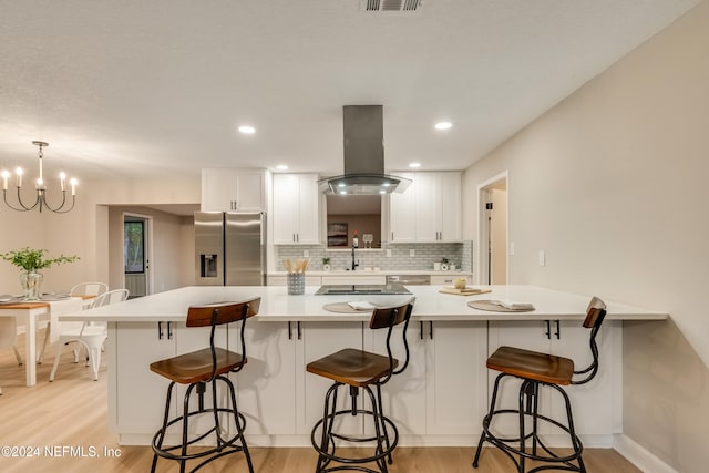 kitchen featuring a kitchen breakfast bar, stainless steel refrigerator with ice dispenser, light hardwood / wood-style flooring, white cabinetry, and island exhaust hood