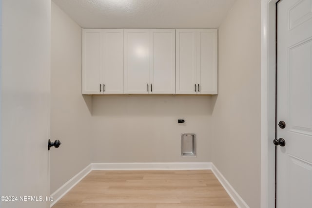 washroom featuring light hardwood / wood-style floors, cabinets, a textured ceiling, and hookup for an electric dryer