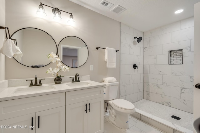 bathroom featuring toilet, vanity, and tiled shower