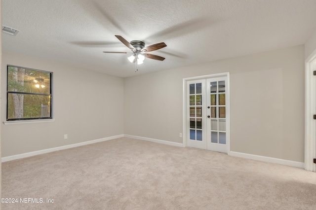 carpeted empty room featuring french doors, a textured ceiling, and ceiling fan