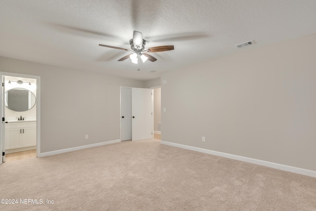 interior space with ceiling fan, sink, light carpet, and ensuite bath