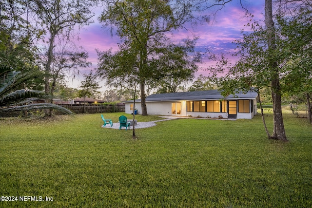 back house at dusk featuring a yard and an outdoor fire pit