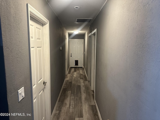 hallway with a textured ceiling and dark wood-type flooring