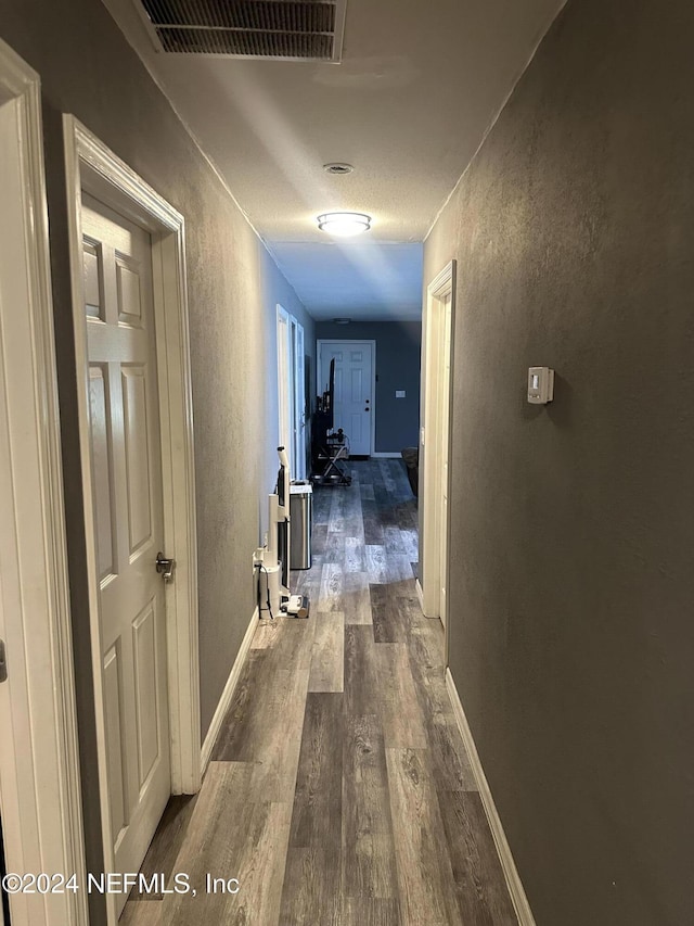 corridor with a textured ceiling and dark hardwood / wood-style floors