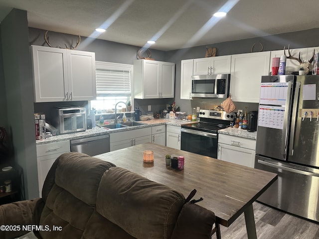 kitchen featuring light stone countertops, white cabinetry, sink, and stainless steel appliances