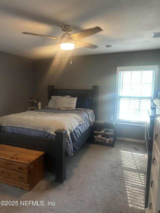 carpeted bedroom featuring ceiling fan and a textured ceiling