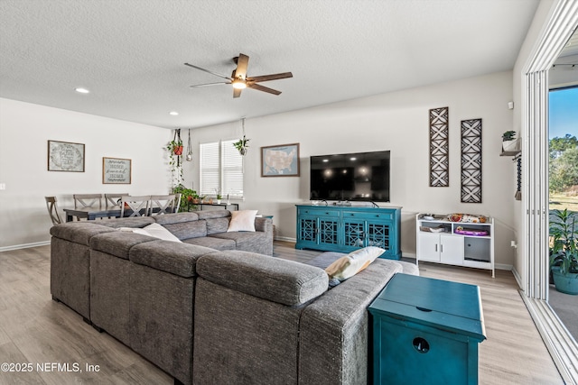 living room with a textured ceiling, light hardwood / wood-style flooring, and ceiling fan