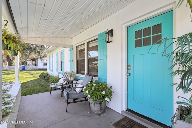 doorway to property with covered porch and a yard