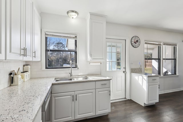 kitchen with backsplash, light stone countertops, white cabinetry, and sink