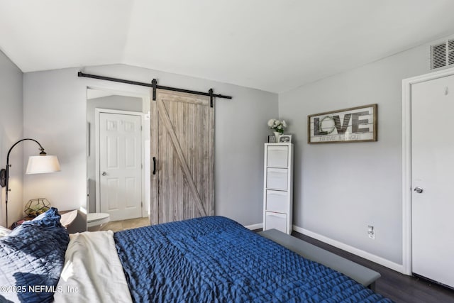 bedroom featuring a barn door, hardwood / wood-style floors, and lofted ceiling