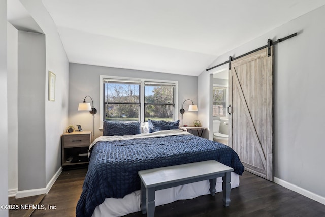 bedroom featuring ensuite bathroom, a barn door, dark hardwood / wood-style flooring, and lofted ceiling