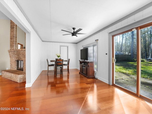 dining area featuring hardwood / wood-style flooring, ceiling fan, and a fireplace