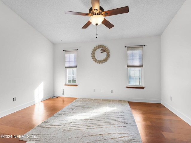 spare room with hardwood / wood-style floors, ceiling fan, and a textured ceiling