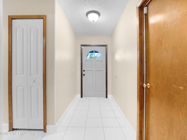 doorway to outside with light tile patterned floors and a textured ceiling