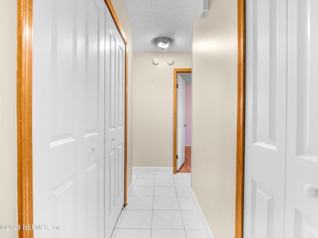 hall with light tile patterned floors and a textured ceiling