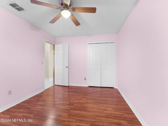 unfurnished bedroom with ceiling fan, dark hardwood / wood-style flooring, and a closet