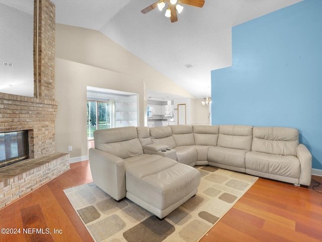 living room featuring a fireplace, hardwood / wood-style floors, vaulted ceiling, and ceiling fan