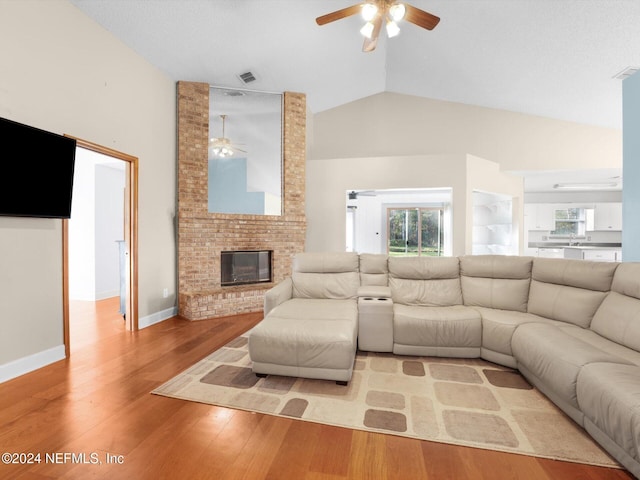 living room featuring ceiling fan, a fireplace, light hardwood / wood-style floors, and lofted ceiling