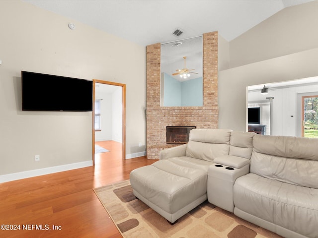 living room featuring a fireplace, light hardwood / wood-style flooring, ceiling fan, and lofted ceiling