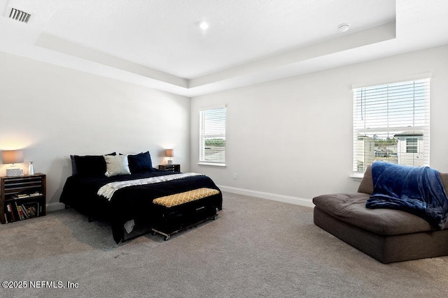 bedroom featuring a tray ceiling and light carpet