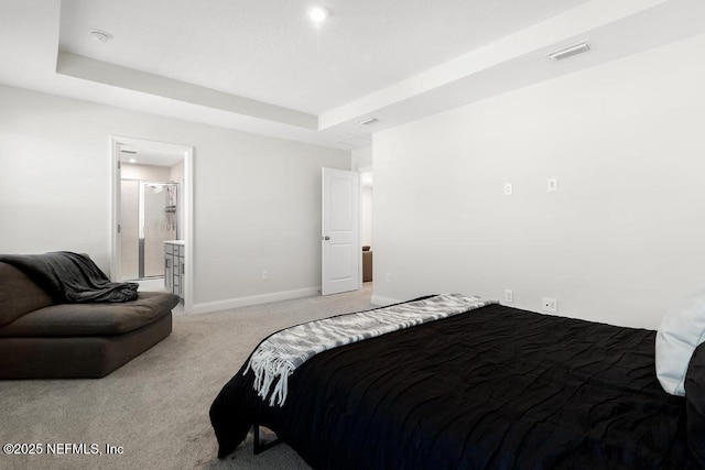 bedroom featuring light carpet, connected bathroom, and a tray ceiling