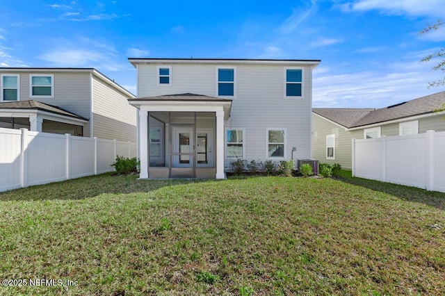 rear view of property with a lawn, central air condition unit, and a sunroom