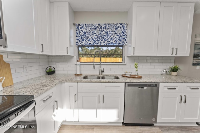 kitchen featuring light stone countertops, tasteful backsplash, stainless steel dishwasher, sink, and white cabinetry