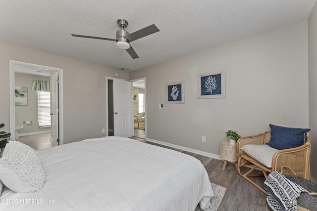 bedroom with connected bathroom, ceiling fan, dark wood-type flooring, and a textured ceiling