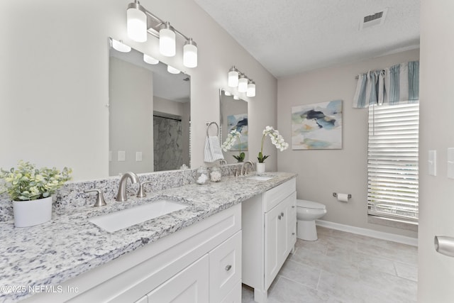 bathroom featuring a wealth of natural light, vanity, a textured ceiling, and toilet