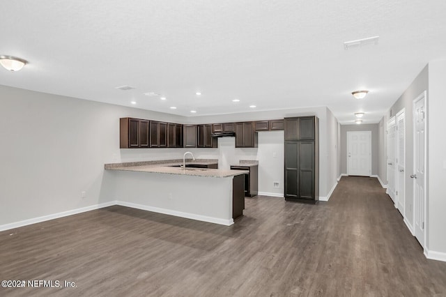 kitchen with dark brown cabinets, dark hardwood / wood-style flooring, kitchen peninsula, and sink