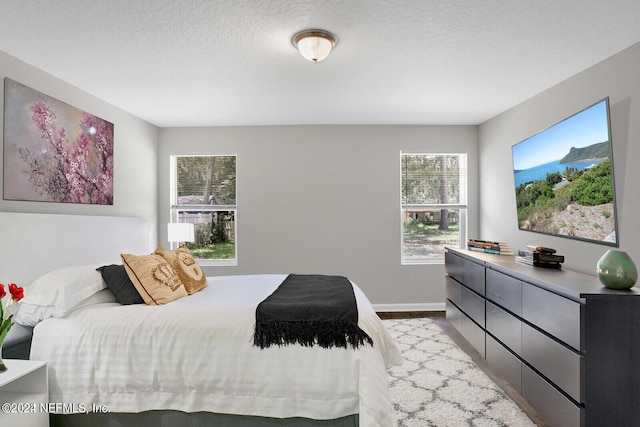 bedroom with multiple windows, light hardwood / wood-style flooring, and a textured ceiling