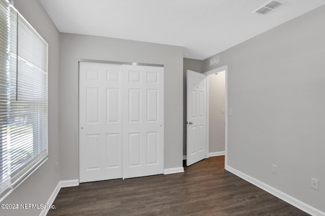 unfurnished bedroom with a closet and dark wood-type flooring