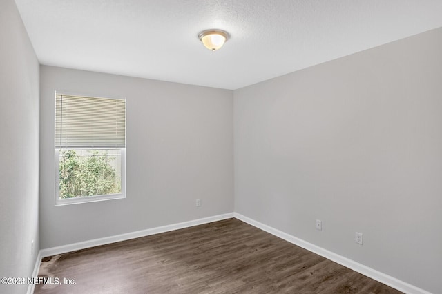 unfurnished room with dark wood-type flooring