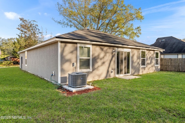 back of house featuring central air condition unit and a lawn