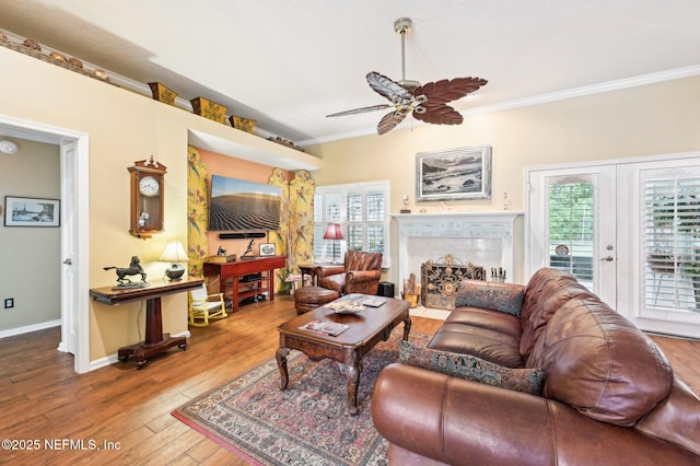 living room featuring french doors, crown molding, hardwood / wood-style flooring, ceiling fan, and a fireplace