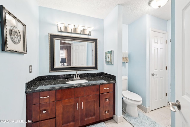 bathroom featuring vanity, tile patterned floors, a textured ceiling, and toilet