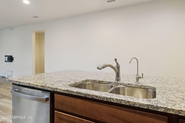 kitchen with light stone counters, dishwasher, light wood-type flooring, and sink