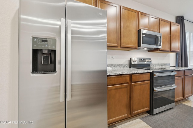 kitchen featuring light stone counters, light wood-type flooring, and stainless steel appliances