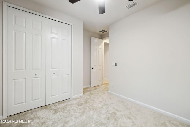 unfurnished bedroom featuring ceiling fan, a closet, and light colored carpet